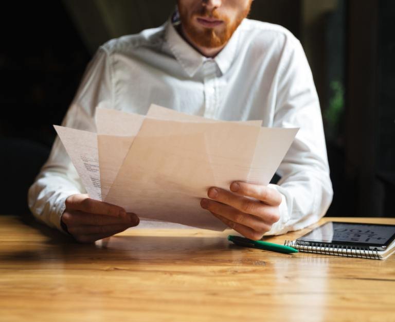 Cropped photo of young readhead bearded man working with papers