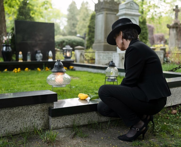 Woman mourning in the cemetery next to grave