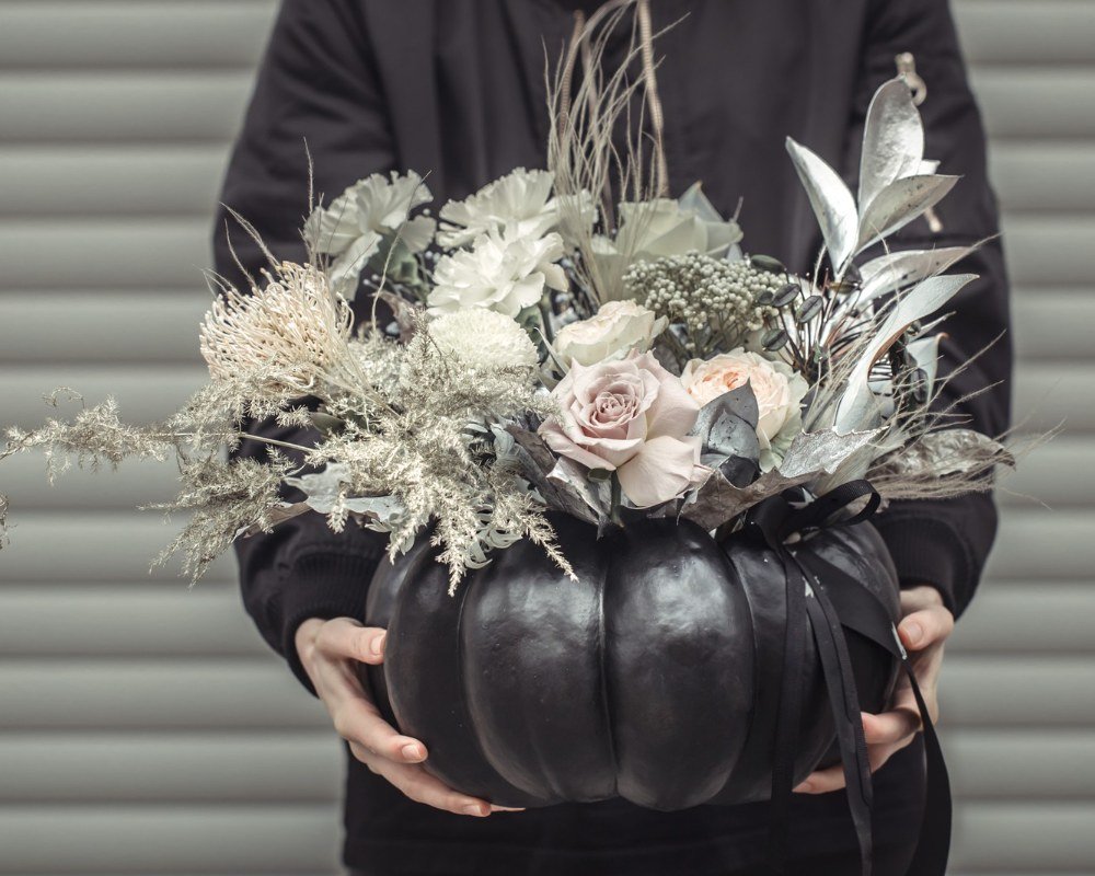 Girl holding a flower arrangement in a pumpkin.