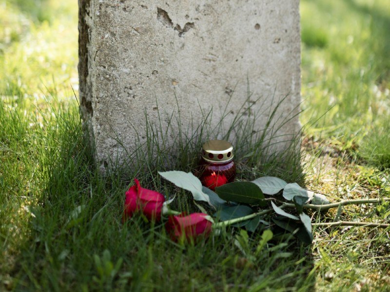 View of gravestone with flowers and candle